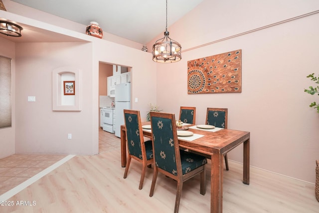 dining space with light wood-style floors and vaulted ceiling