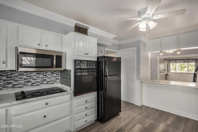 kitchen with white cabinets, decorative backsplash, light hardwood / wood-style floors, black appliances, and crown molding