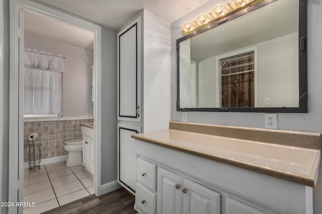 bathroom featuring tile patterned floors, vanity, toilet, and tile walls