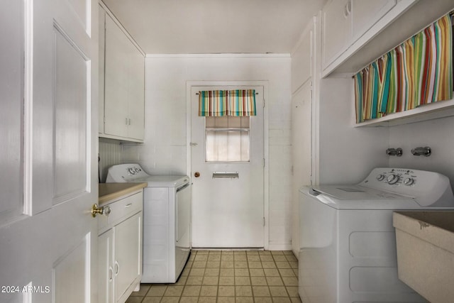 clothes washing area featuring cabinets, sink, and washer and dryer