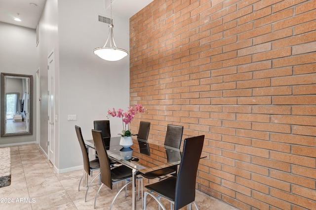 dining area featuring a high ceiling and brick wall