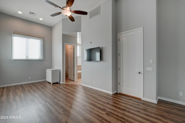 interior space with ceiling fan, dark wood-type flooring, and a high ceiling