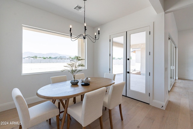 dining area featuring a mountain view, a notable chandelier, french doors, and light wood-type flooring