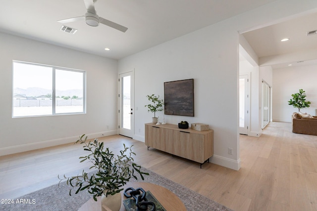 living room with a mountain view, ceiling fan, and light hardwood / wood-style flooring