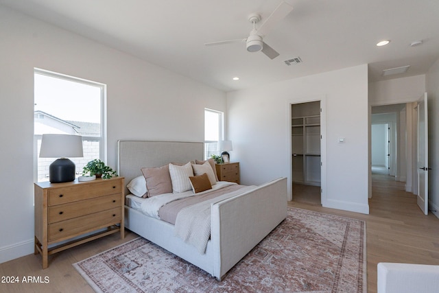 bedroom with ceiling fan, a spacious closet, light hardwood / wood-style floors, and a closet