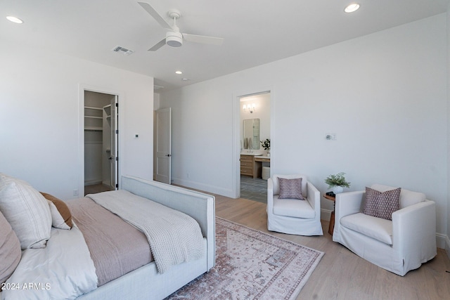 bedroom with ceiling fan, ensuite bathroom, a spacious closet, a closet, and light wood-type flooring