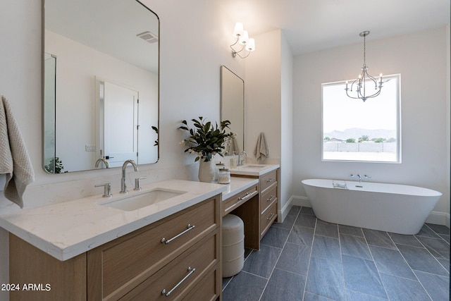 bathroom with an inviting chandelier, vanity, and a washtub