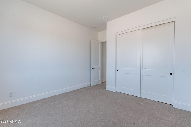 unfurnished bedroom featuring light carpet and a closet