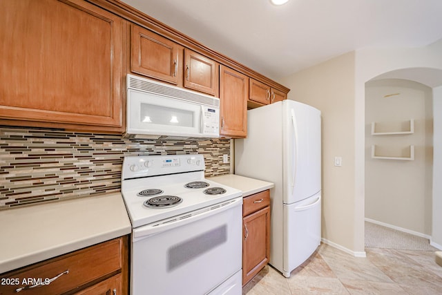 5249 E Shea Blvd Unit 215, Scottsdale, AZ 85254 - kitchen with white appliances, brown cabinets, light countertops, decorative backsplash, and arched walkways