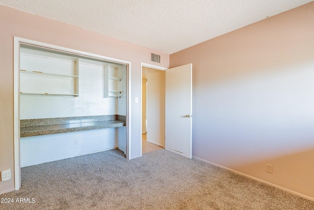 unfurnished bedroom with a textured ceiling, a closet, and light carpet