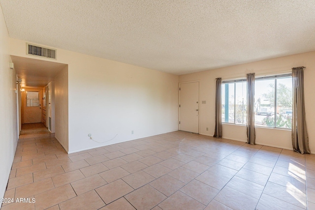 unfurnished room featuring a textured ceiling and light tile patterned floors