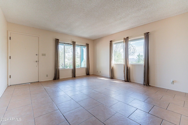 tiled spare room featuring plenty of natural light and a textured ceiling