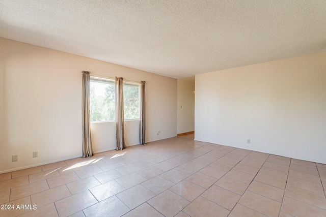 tiled spare room featuring a textured ceiling