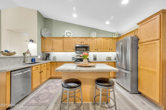 46068 W Guilder Ave, Maricopa, AZ 85139 - kitchen featuring appliances with stainless steel finishes, lofted ceiling, a kitchen island, light wood-style floors, and backsplash