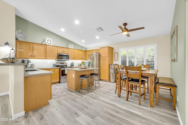 46068 W Guilder Ave, Maricopa, AZ 85139 - kitchen with appliances with stainless steel finishes, light wood-type flooring, a kitchen island, ceiling fan, and decorative backsplash