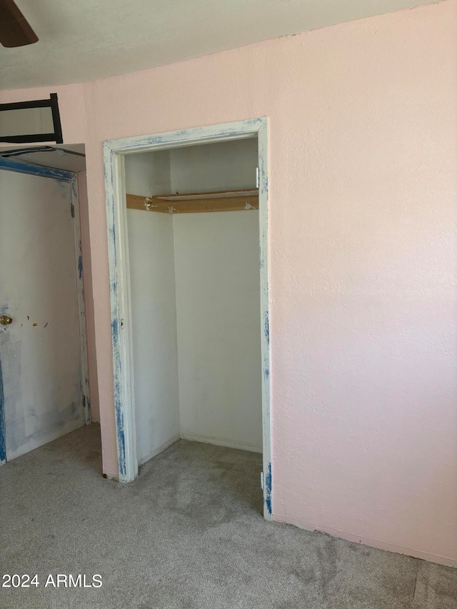 interior space with a closet, light colored carpet, and ceiling fan