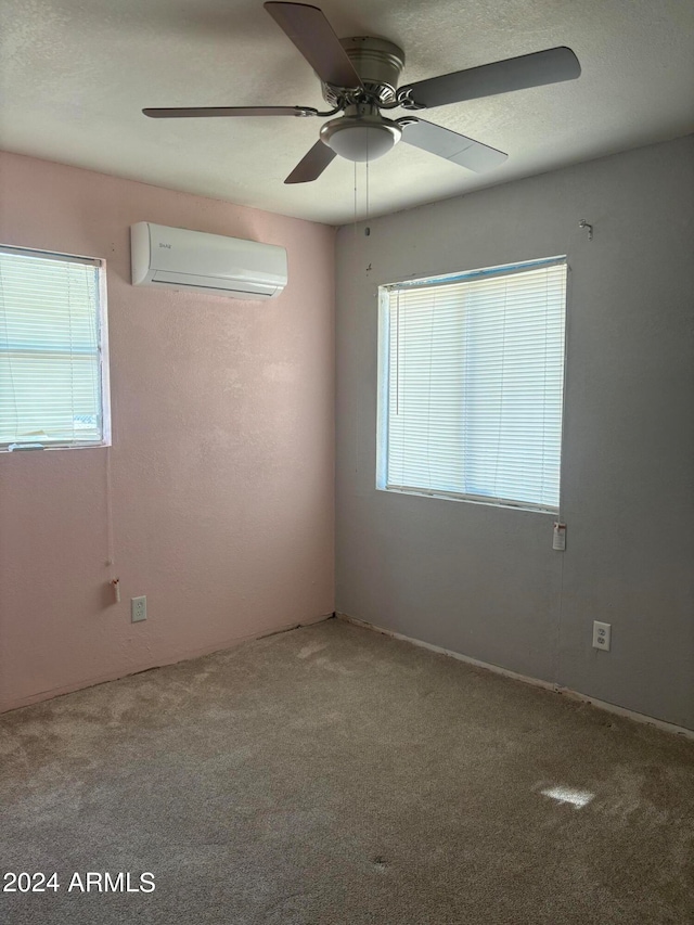 spare room featuring an AC wall unit, ceiling fan, and carpet floors