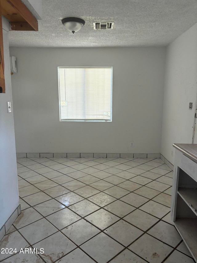 tiled empty room with a textured ceiling