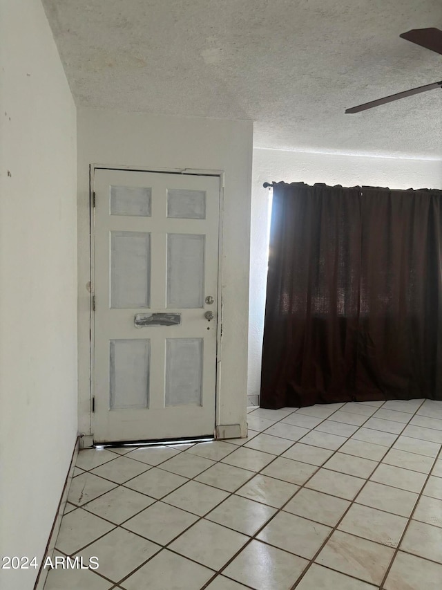 entryway with a textured ceiling and light tile patterned floors