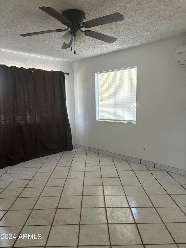 spare room featuring a textured ceiling, light tile patterned floors, ceiling fan, and a wall mounted air conditioner