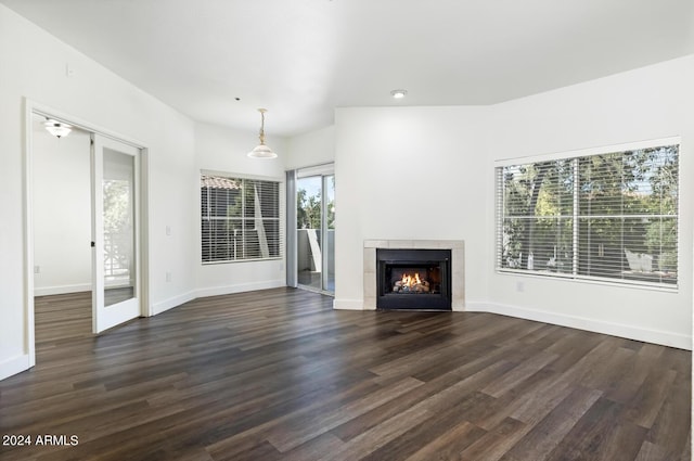 unfurnished living room with dark wood-type flooring and a tile fireplace