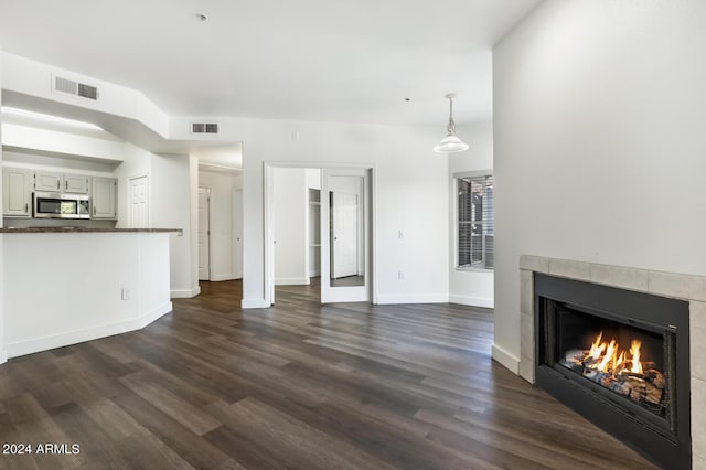 unfurnished living room with a tile fireplace and dark wood-type flooring