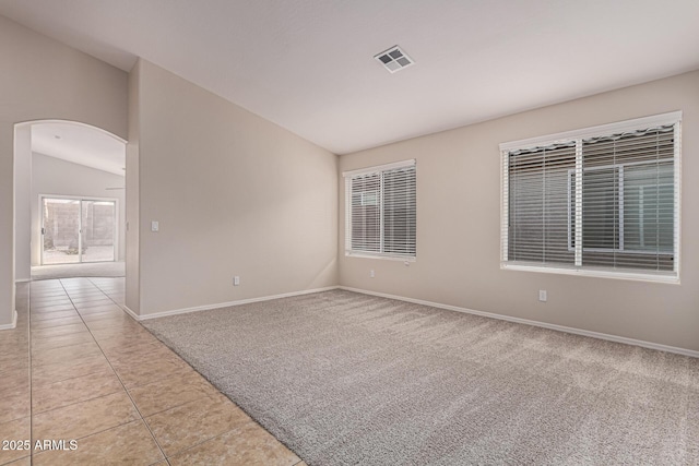 tiled empty room featuring vaulted ceiling