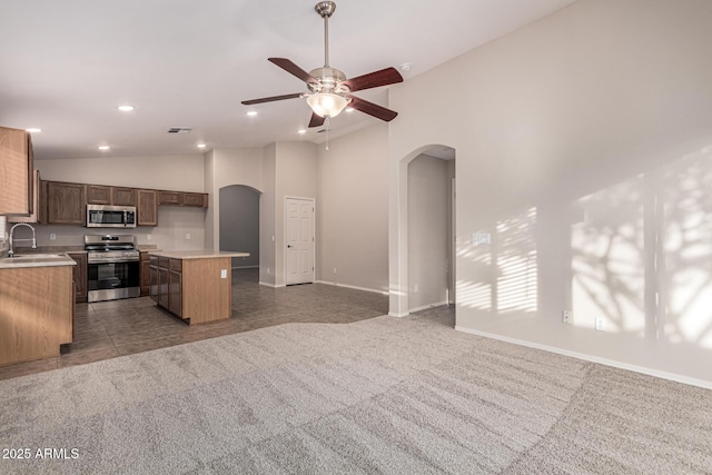 kitchen with ceiling fan, sink, a center island, carpet floors, and appliances with stainless steel finishes