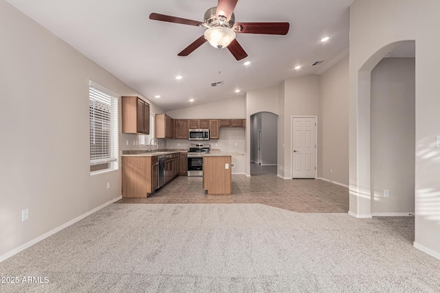 kitchen featuring stainless steel appliances, light colored carpet, ceiling fan, sink, and a kitchen island