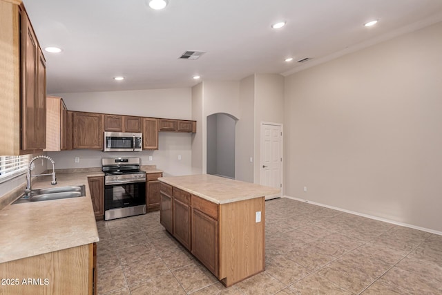 kitchen with light tile patterned flooring, sink, a kitchen island, and stainless steel appliances