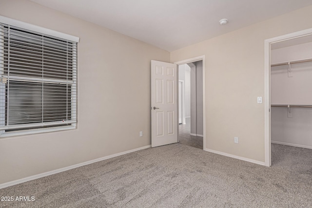 unfurnished bedroom with carpet, a walk in closet, and a closet