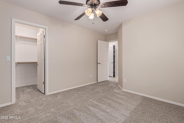 unfurnished bedroom featuring ceiling fan, a walk in closet, light carpet, and a closet