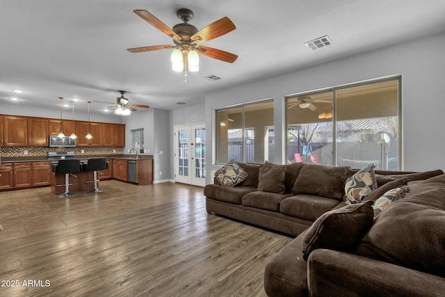 living room with french doors, wood-type flooring, sink, and plenty of natural light