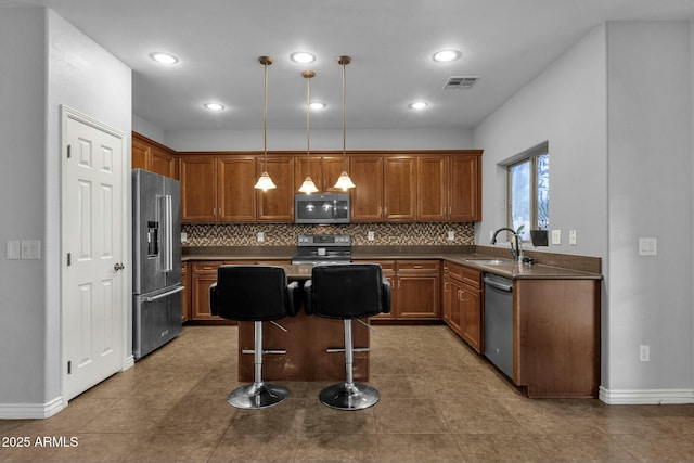 kitchen with sink, a breakfast bar, stainless steel appliances, a center island, and decorative light fixtures