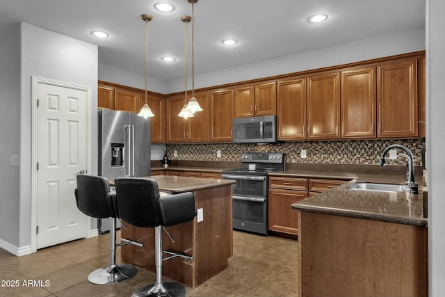 kitchen featuring sink, a breakfast bar area, hanging light fixtures, stainless steel appliances, and a center island