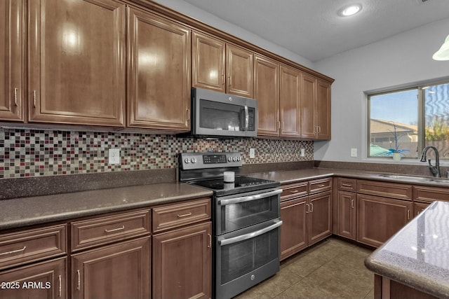 kitchen featuring appliances with stainless steel finishes, sink, decorative backsplash, and dark tile patterned floors