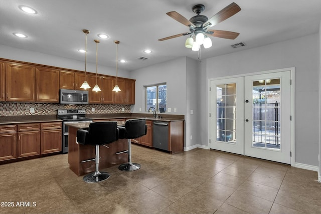 kitchen with a breakfast bar area, hanging light fixtures, stainless steel appliances, decorative backsplash, and french doors