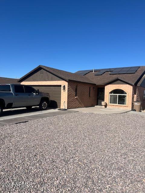 ranch-style home with solar panels and a garage