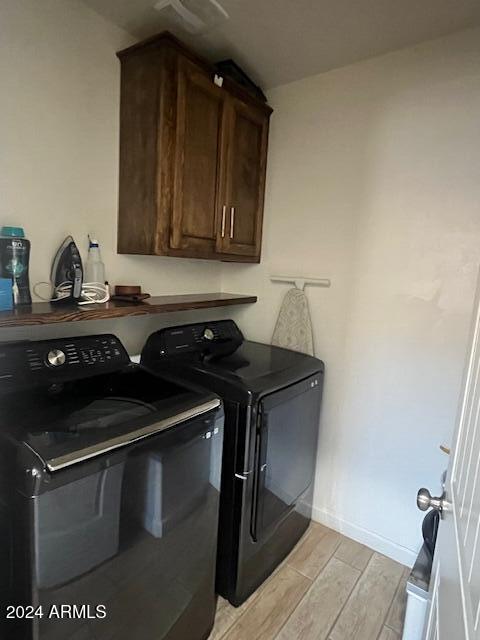 clothes washing area featuring cabinets and washer and clothes dryer