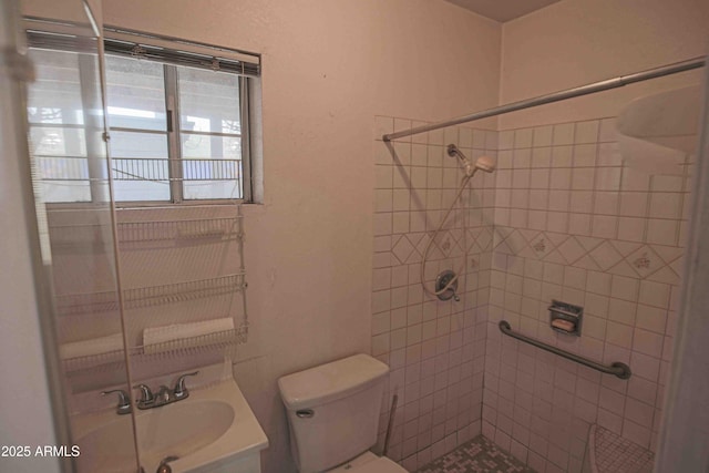 bathroom with a tile shower, vanity, and toilet