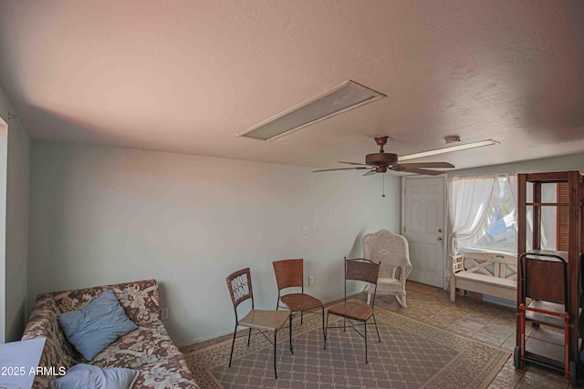 living area with a textured ceiling and ceiling fan