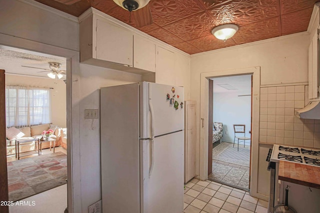 kitchen featuring white cabinets, white appliances, ornamental molding, ceiling fan, and light tile patterned floors