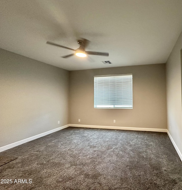 unfurnished room with baseboards, a ceiling fan, dark carpet, and visible vents