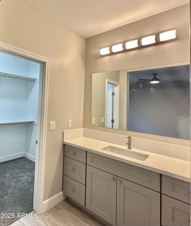 bathroom with a textured wall, vanity, a textured ceiling, baseboards, and wood finished floors