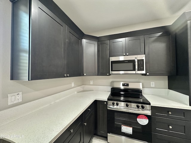 kitchen featuring dark cabinets and appliances with stainless steel finishes
