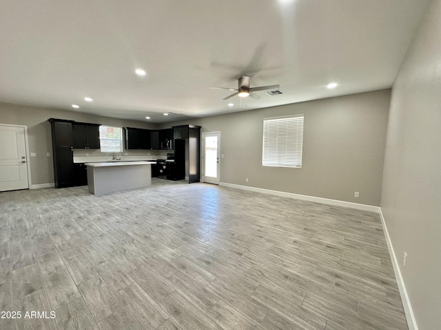 unfurnished living room with visible vents, a ceiling fan, baseboards, and recessed lighting