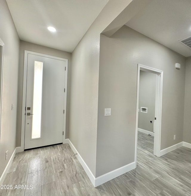 entryway with baseboards, light wood finished floors, and visible vents