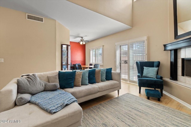 living room featuring ceiling fan, wood-type flooring, and a fireplace