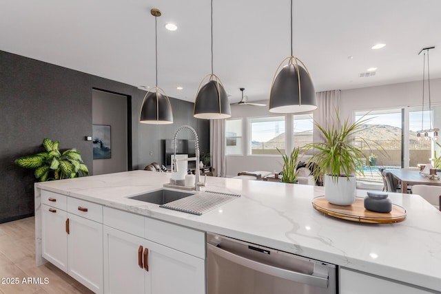 kitchen featuring pendant lighting, sink, white cabinetry, light stone counters, and stainless steel dishwasher