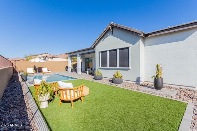 back of property with a fenced in pool, a patio area, and a lawn